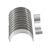 A gleaming set of metallic engine bearing shells from the Partsology Engine Rebuild Kit for the Saturn L300 with a 3.0L V6 DOHC, arranged in a curve, with one shell standing upright separately on the right. The shells reflect light, highlighting their smooth, polished surface.